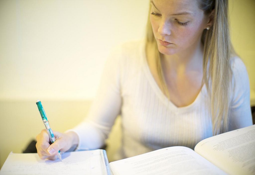 Mulher loira, anotando em seu caderno o cronograma do Enem 2025.
