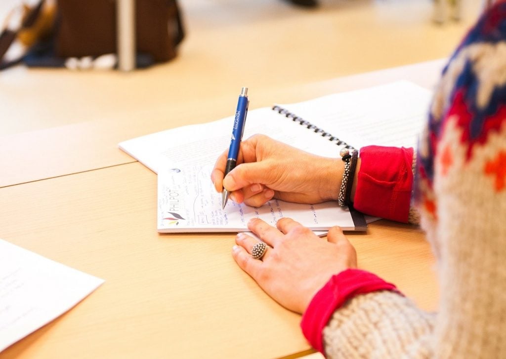 Mulher escrevendo uma redação, se preparando para o Enem 2025
