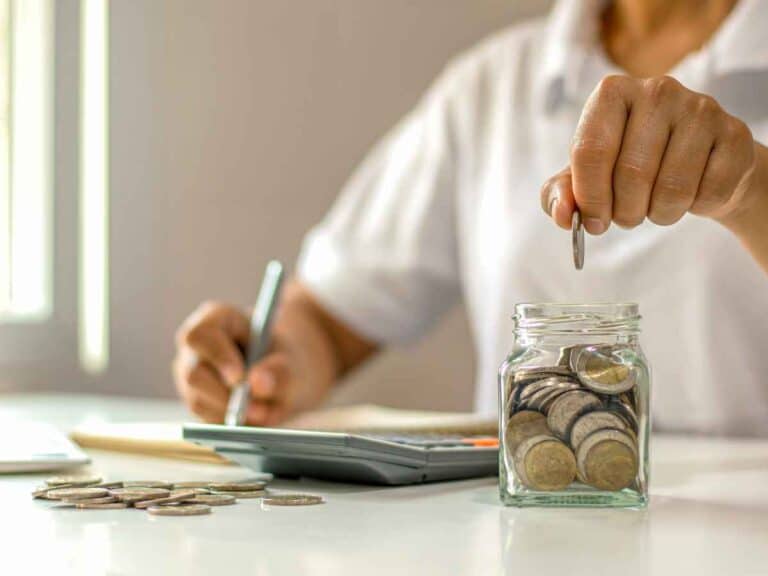 Pessoa acrescentando moeda de 1 real de Juscelino Kubitschek em sua coleção de moedas comemorativas.