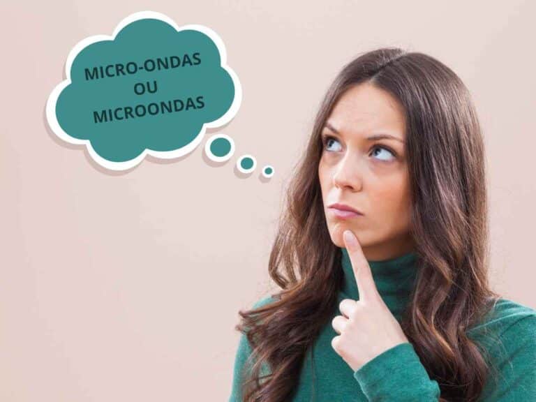 Mulher com uma expressão reflexiva, pensando na forma correta de escrever microondas ou micro-ondas. Ela usa uma blusa ver e tem um balão de pensamento escrito "Micro-ondas ou Microondas". Fundo bege sólido