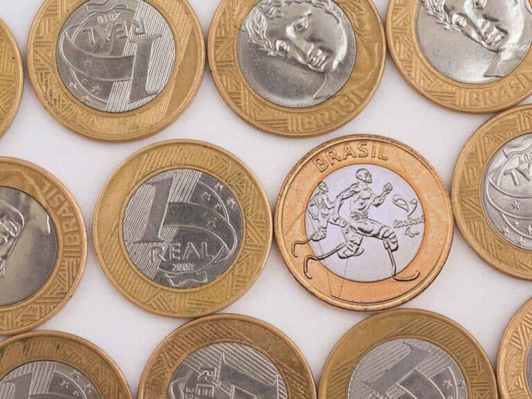 Moedas de 1 real, com destaque para uma moeda comemorativa do atletismo, ilustrando exemplos de moedas raras valorizadas por colecionadores.