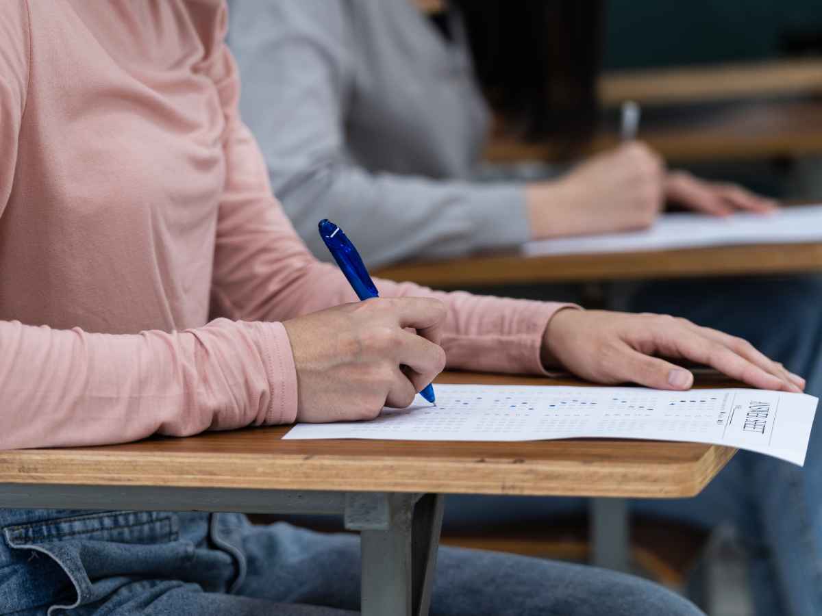 Pessoa escrevendo uma redação, representando a participação em concurso público.