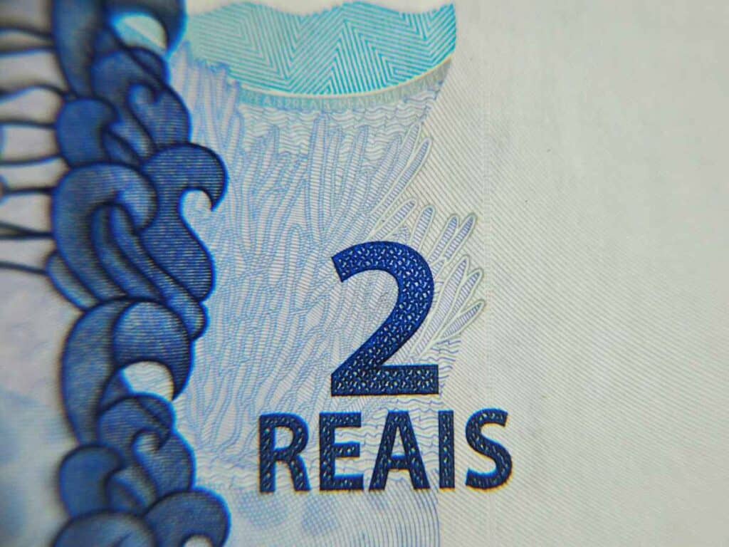 Close-up da inscrição “2 reais” em nota brasileira, destacando detalhes de segurança e textura da cédula.