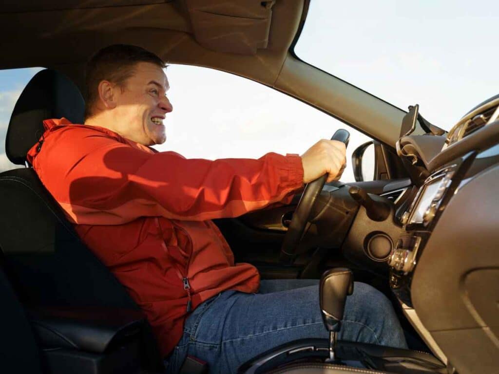 Homem ao volante realiza uma frenagem emergencial, demonstrando tensão e esforço enquanto segura firme o volante.